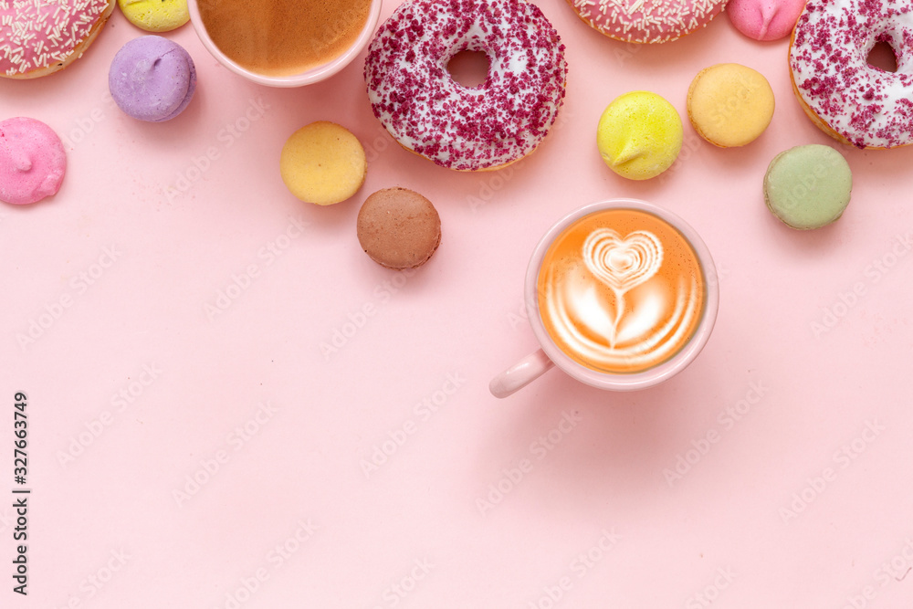 Two  Coffee cups, delicious pink donuts with sprinkle and colorful bright macaroons on pink paper background