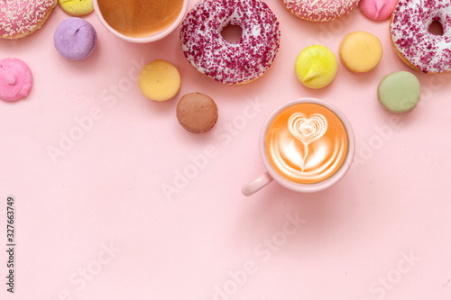 Two  Coffee cups  delicious pink donuts with sprinkle and colorful bright macaroons on pink paper background