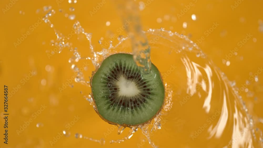 Water spinning off kiwi on yellow background.  Shot in slow motion with Phantom Flex 4K camera.