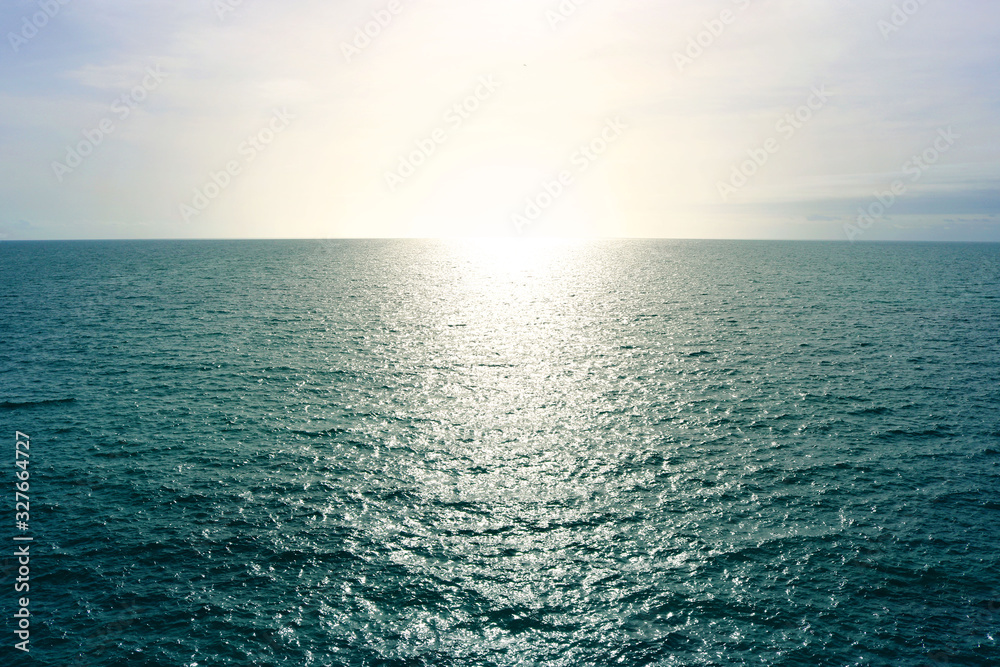Obraz premium Atlantic ocean horizon line at sunset, with blue sea water with calm waves and yellow warm sun - evocative deep seascape wallpaper