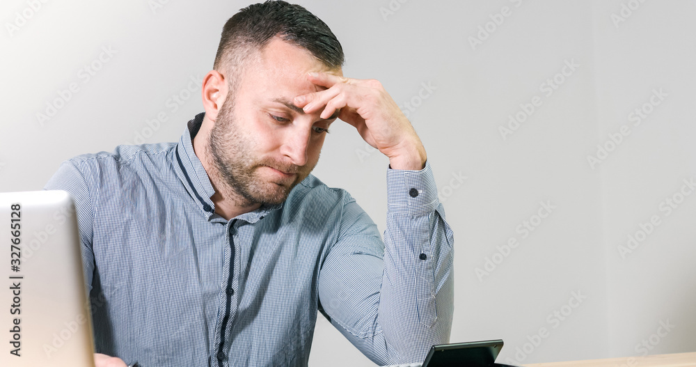 Fototapeta premium Frustrated businessman under stress nervously filling 1040 tax form with calculator at office desk.