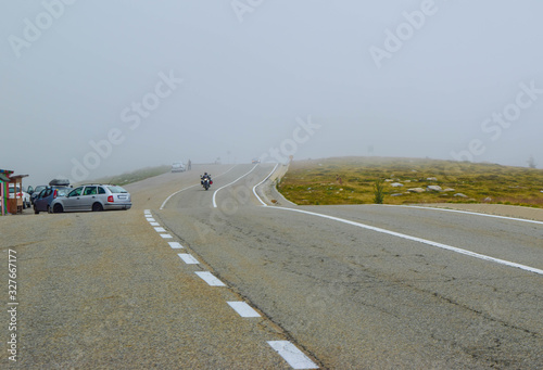 Motorcyclist and cars in fog on the Transalpina road DN67C. This is one of the most beautiful alpine routes in Romania and the highest mountain asphalt road in Romania and  Carpathians mountains.