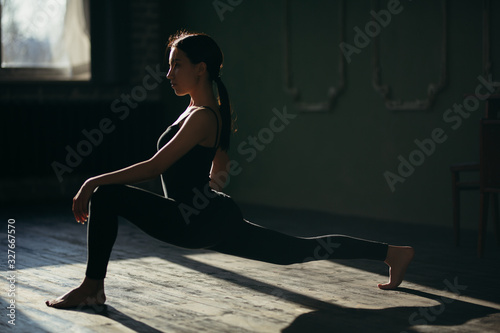 Girl in black sportswear doing yoga on the floor in the gym.