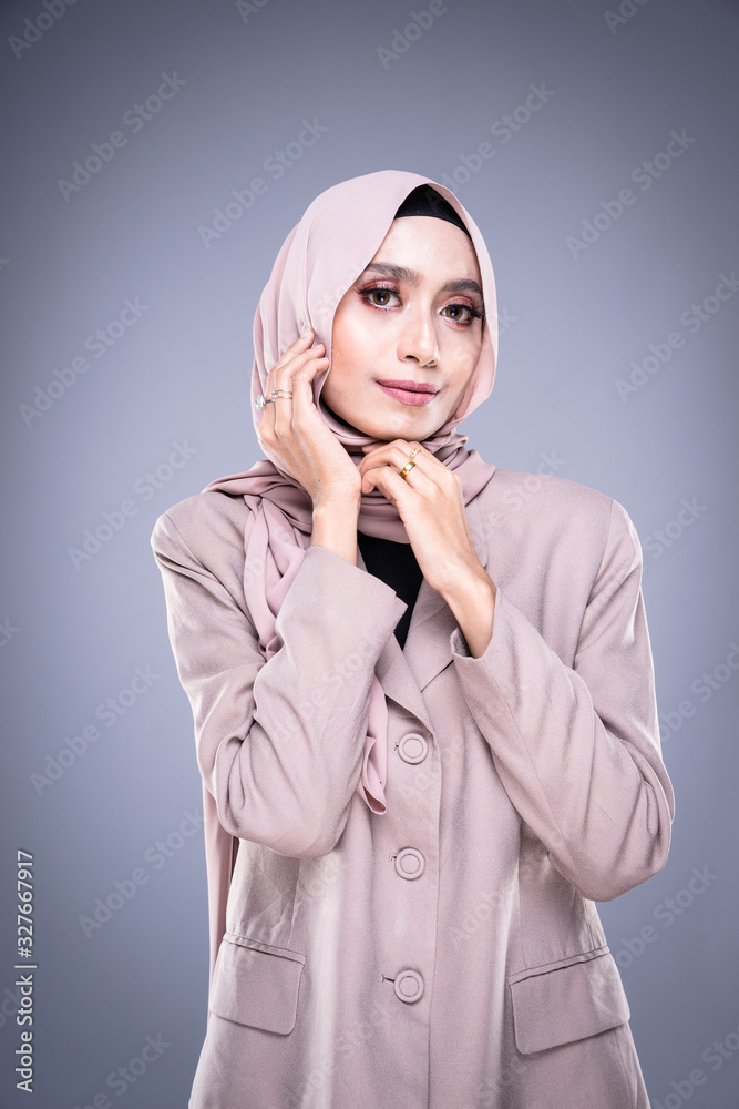 Half length portrait of a beautiful Muslim female model in a hijab and officewear isolated on grey background. Hijab and Muslim fashion lifestyle concept Half length portrait of a beautiful Muslim female model in a hijab and officewear isolated on grey background. Hijab and Muslim fashion lifestyle concept
