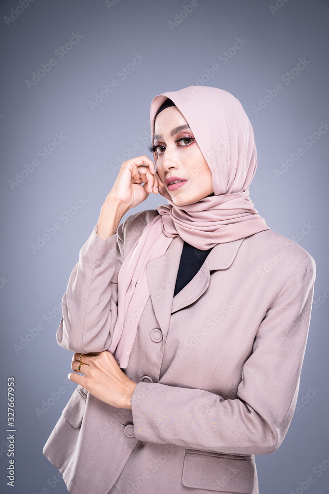 Half length portrait of a beautiful Muslim female model in a hijab and officewear isolated on grey background. Hijab and Muslim fashion lifestyle concept Half length portrait of a beautiful Muslim female model in a hijab and officewear isolated on grey background. Hijab and Muslim fashion lifestyle concept