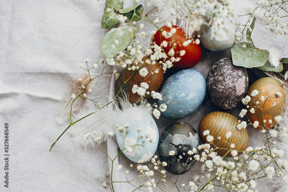 Stylish easter eggs in rustic nest on table flat lay. Natural dyed colorful easter eggs with spring white flowers and feathers on rural textile background. Happy Easter Stylish easter eggs in rustic nest on table flat lay. Natural dyed colorful easter eggs with spring white flowers and feathers on rural textile background. Happy Easter