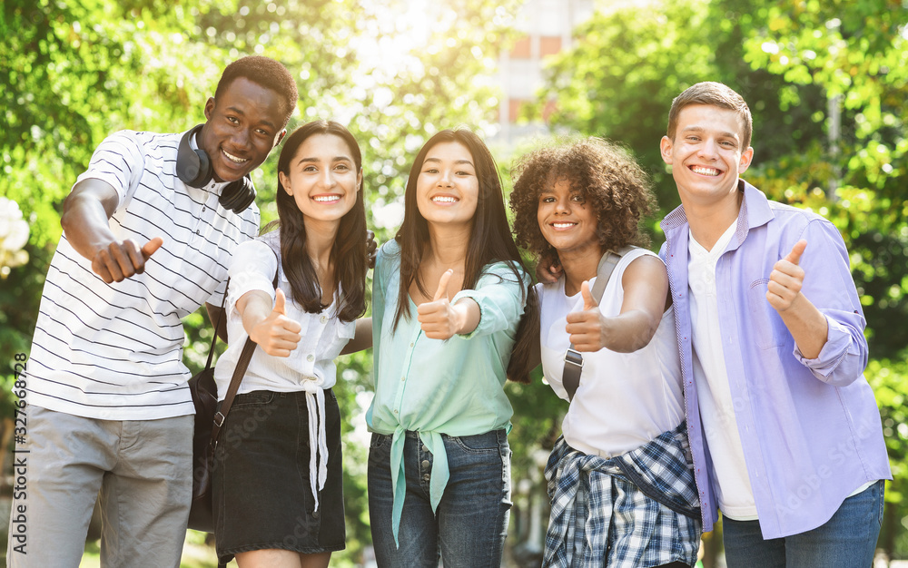 Happy Multicultural Teens Posing Together Outdoors And Showing Thumb Up Happy Multicultural Teens Posing Together Outdoors And Showing Thumb Up