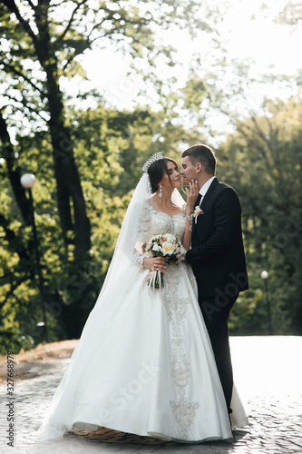 Loving wedding couple outdoor. Bride and groom. Wedding couple. Close up of a newlywed couple, a bride with a beautiful hair style and make up. Happy newlywed couple walking in the park.