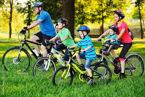 Young large family on bicycles in the Park against the background of greenery and trees.family Day