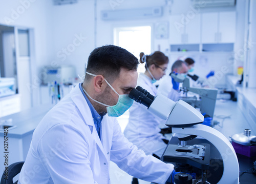 Biologists looking through microscope in laboratory
