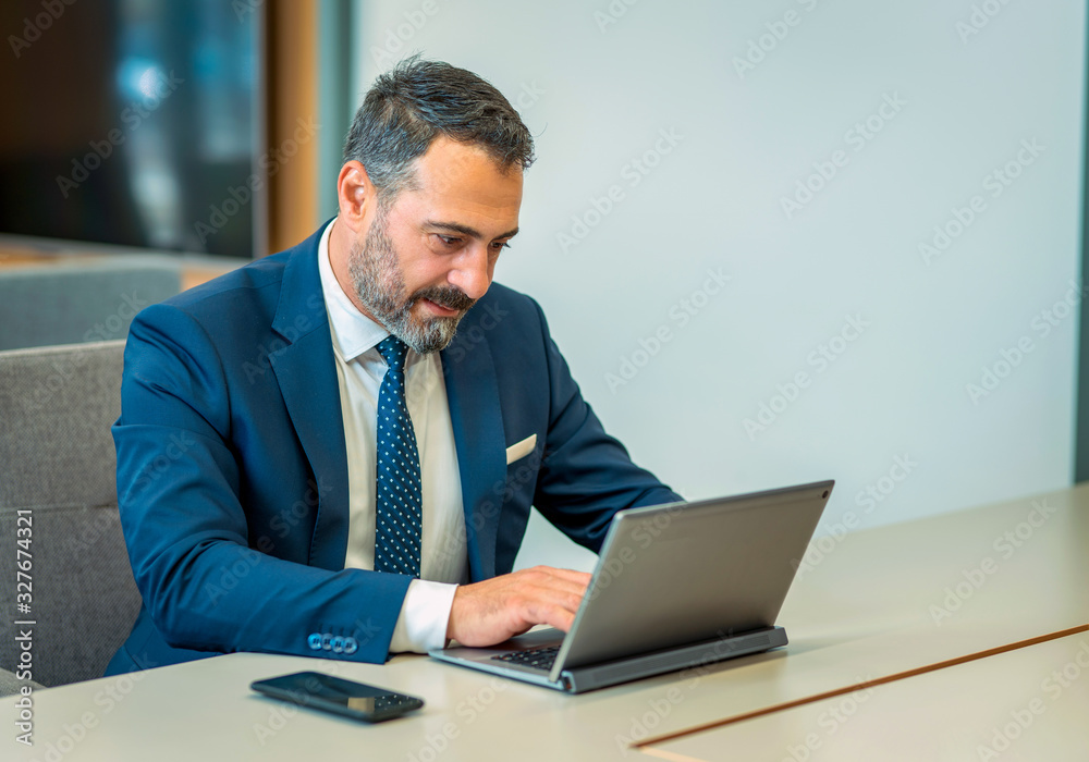 A suit-wearing, bearded and handsome employee who trades on his computer A suit-wearing, bearded and handsome employee who trades on his computer
