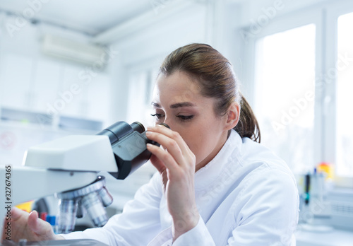 Woman biologist looking through microscope
