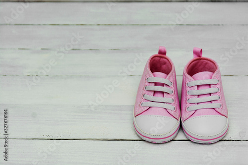 Pink baby girl sneakers, sport shoes close up on gray background. Newbord, motherhood, pregnancy concept with copy space. photo