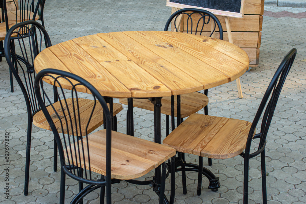 Wooden table with chairs for relax. Street cafe - tables and chairs stand on the street for food and snacks. Table and chair Wooden table with chairs for relax. Street cafe - tables and chairs stand on the street for food and snacks. Table and chair