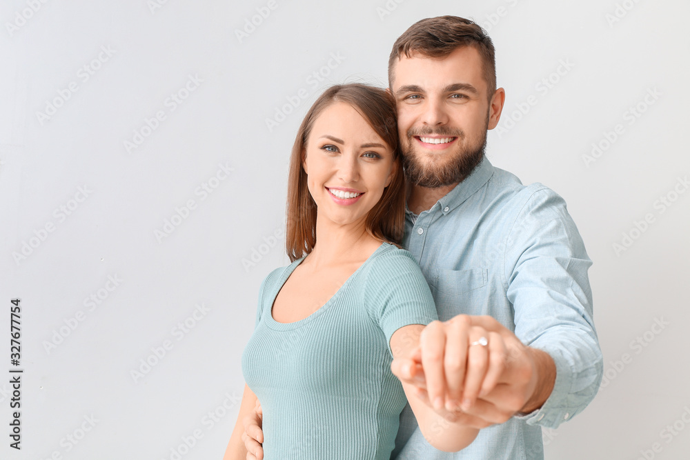 Happy engaged young couple on light background Happy engaged young couple on light background