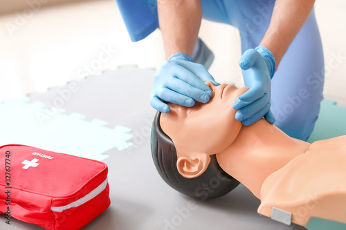 Instructor demonstrating CPR on mannequin at first aid training course photo