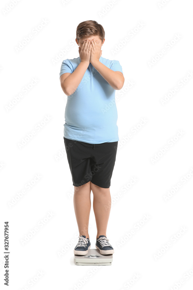 Overweight boy standing on scales against white background