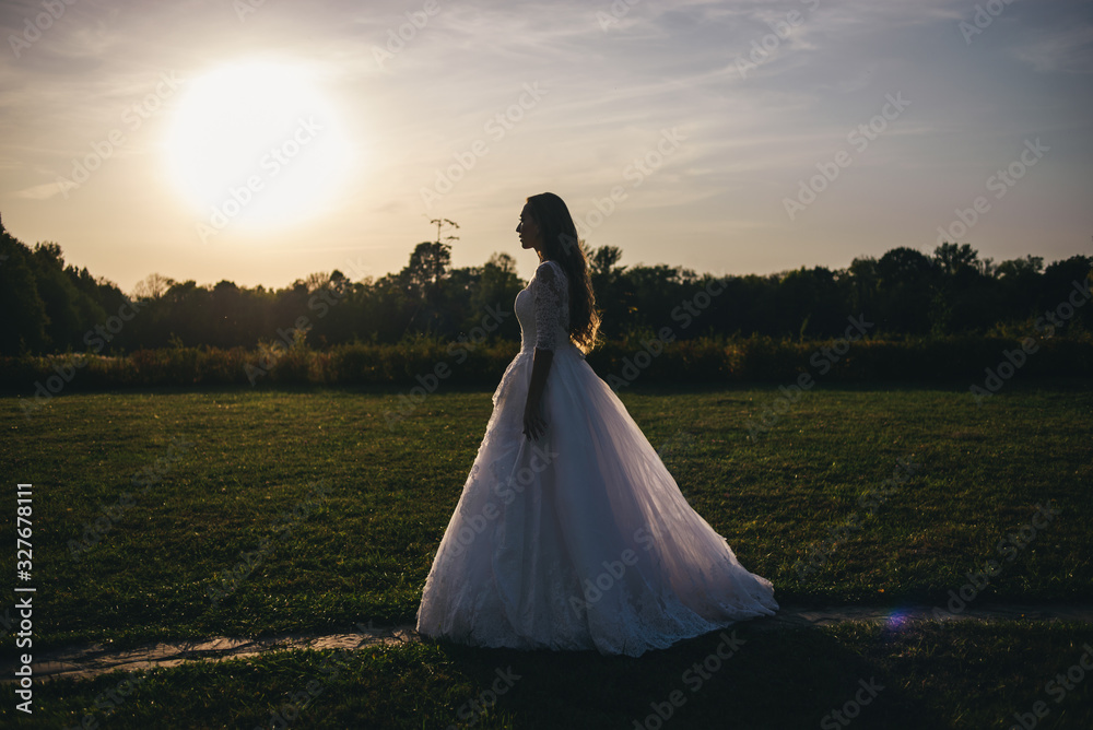 Beautiful young woman in a white wedding dress and black boots at sunset is photographed. Beautiful young woman in a white wedding dress and black boots at sunset is photographed.