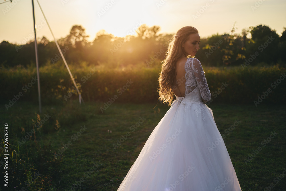 Beautiful young woman in a white wedding dress and black boots at sunset is photographed. Beautiful young woman in a white wedding dress and black boots at sunset is photographed.