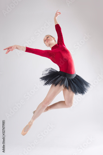 Young woman ballet dancer leaping in a black tutu.