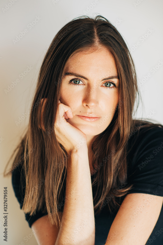 Close up portrait of beautiful young woman wearing black t-shirt, posing on white background Close up portrait of beautiful young woman wearing black t-shirt, posing on white background