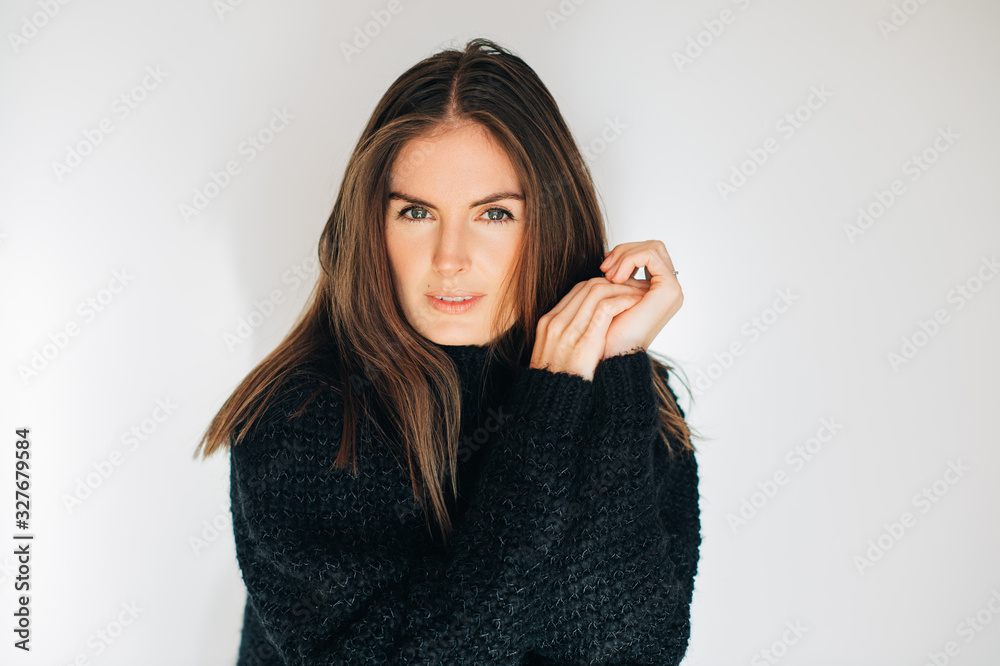 Close up portrait of beautiful young woman wearing black pullover, posing on white background Close up portrait of beautiful young woman wearing black pullover, posing on white background