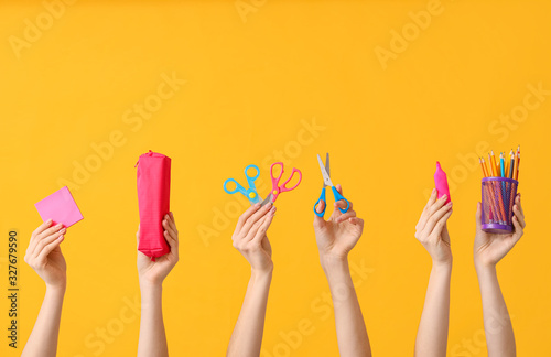Many hands with school supplies on color background