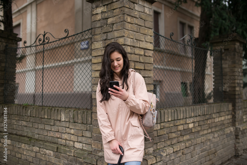Girl with black hair standing in street and using mobile phone Girl with black hair standing in street and using mobile phone