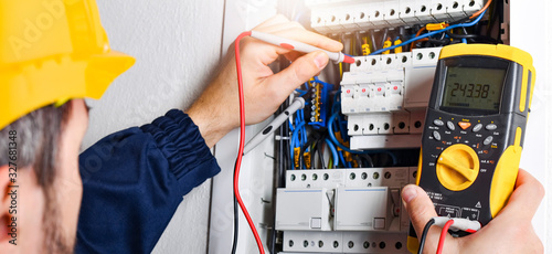 Electrician installing electric cable wires of fuse switch box. photo