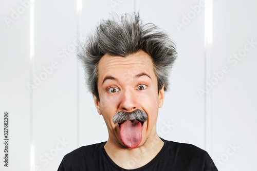Photo Portrait of jocular aging man with grey long hair sticking his tongue out in Einstein manner