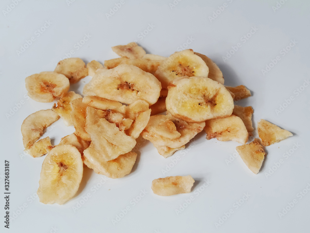 Dried banana chips on a light grey background. Dried banana chips on a light grey background.