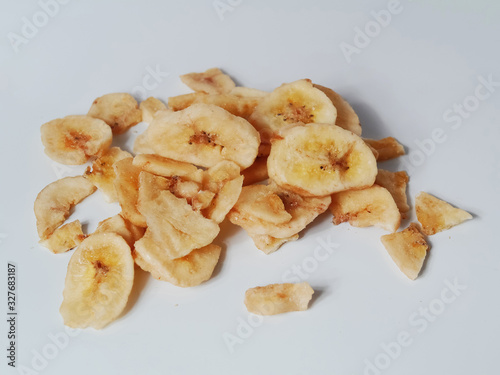 Dried banana chips on a light grey background.