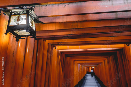 Old lamp and torii gates path at Fushimi Inari taisha shrine, Kyoto