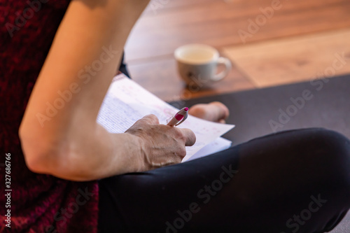 The unrecognizable female studying hard and making notes on a pad. The girl doing homework sitting on the floor. A making notes woman