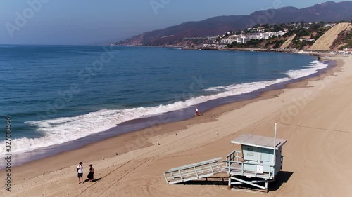 People walk on Pacific Palisades beach, panning aerial