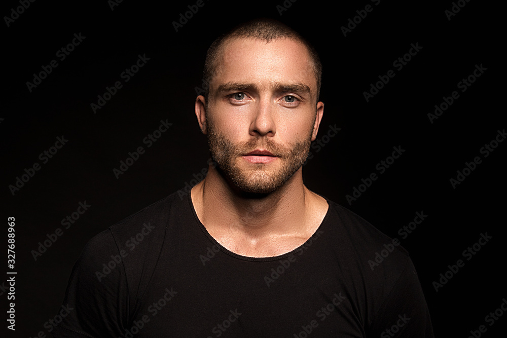 Muscle strong beautiful stripped male model with black t-shirt in denim blue jeans on black isolated font background