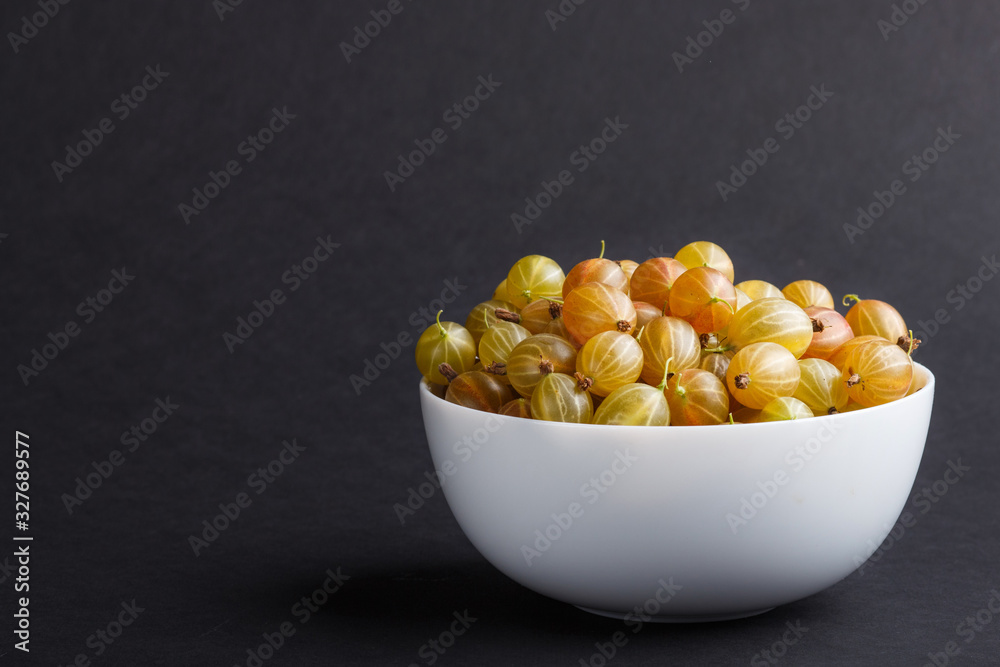 Fresh green gooseberry in white bowl on black background. side view. Fresh green gooseberry in white bowl on black background. side view.