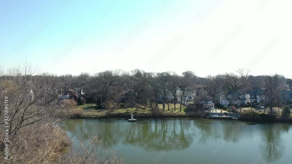 a slow pedestal up in front of some leafless trees, with a green pond in the background. It is a sunny morning on Long Island, New York a slow pedestal up in front of some leafless trees, with a green pond in the background. It is a sunny morning on Long Island, New York