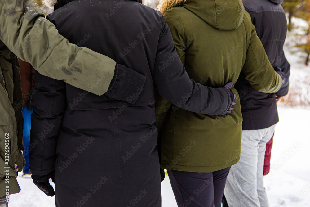 People hug each other and stand around. The warmly dressed unrecognizable people stand outdoors and hug each other. A friendship People hug each other and stand around. The warmly dressed unrecognizable people stand outdoors and hug each other. A friendship