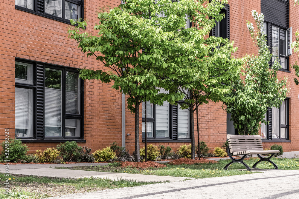 Green trees in front of a modern brick building