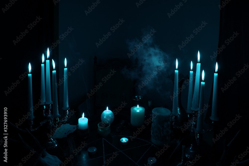 in a dark room on a round esoteric table candles burn, smoke, animal ...