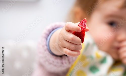Macro Close up of Baby Hand with a Piece of Fruits Sitting in Child's Chair Kid Eating Healthy Food