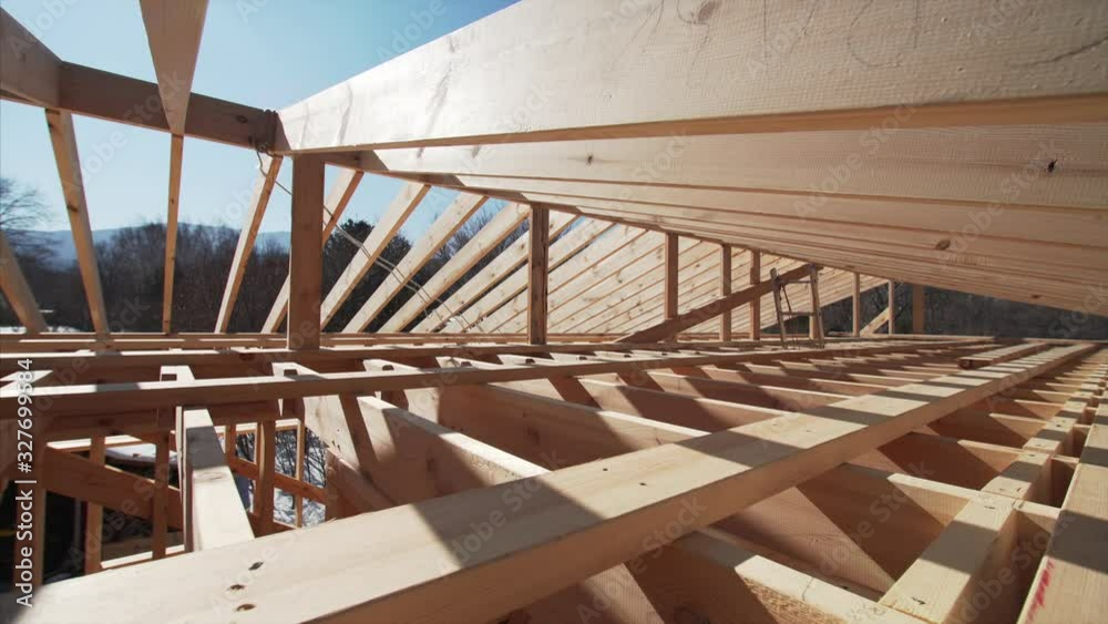 Camera is moving forward, view of the area under wooden roof beams, future attic of the frame house under construction Camera is moving forward, view of the area under wooden roof beams, future attic of the frame house under construction