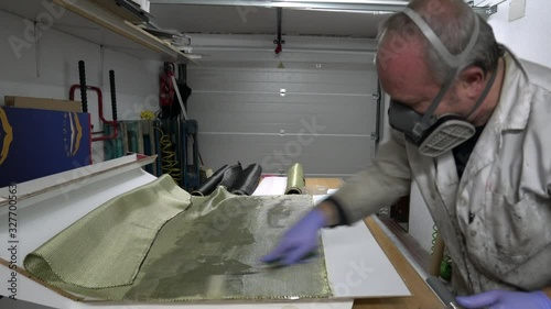 Worker Specialist in composite with protective mask and gloves, manufacturing carbon / kevlar piece with epoxy resin for racing car, in the workshop.