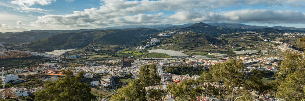 Super wide panorama. Aerial view of historic town Arucas with impressive cathedral. Warm sunny day, bright blue sky and beautiful white clouds. Gran Canaria, Canary islands, Spain