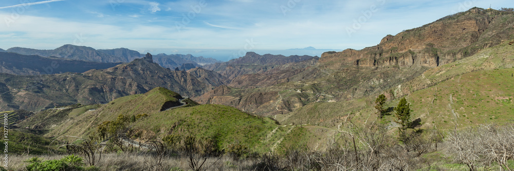 Super wide panorama. Aerial view of the center of Gran Canaria. Famous Bentayga rock in huge caldera and Tenerife above the horizon. Warm sunny day, bright blue sky and beautiful white clouds