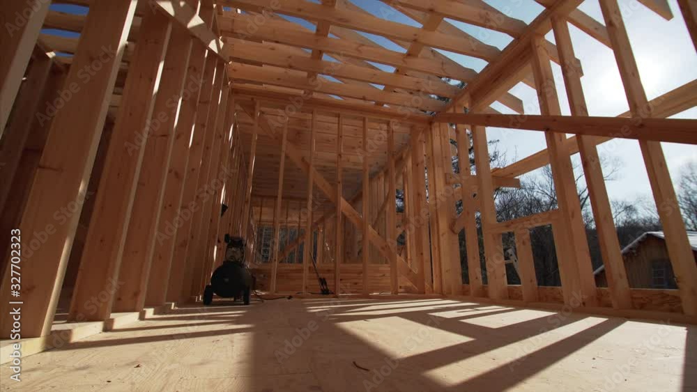 Interior of spacious empty room of the house under construction. Bright sun is shining through the walls beams Interior of spacious empty room of the house under construction. Bright sun is shining through the walls beams