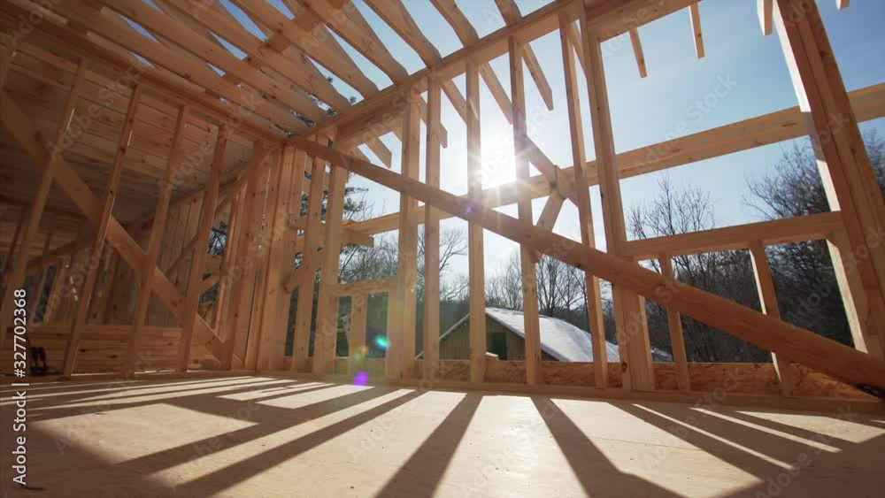 Panoramic view: interior of spacious empty room of the house under construction. Bright sun is shining through the walls beams Panoramic view: interior of spacious empty room of the house under construction. Bright sun is shining through the walls beams