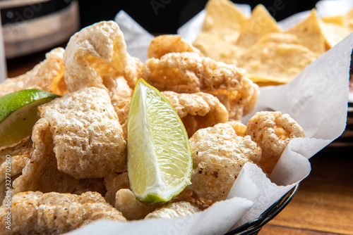 Pork Rinds also called chicharron or chicharrones and tortilla chips with salsa photo