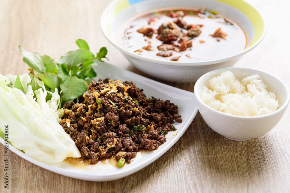 Traditional Northern Thai food, spicy minced pork salad (Larb Moo Kua) and spicy Thai curry soup with beef guts (Kaeng Om Nua) eating with sticky rice Traditional Northern Thai food, spicy minced pork salad (Larb Moo Kua) and spicy Thai curry soup with beef guts (Kaeng Om Nua) eating with sticky rice